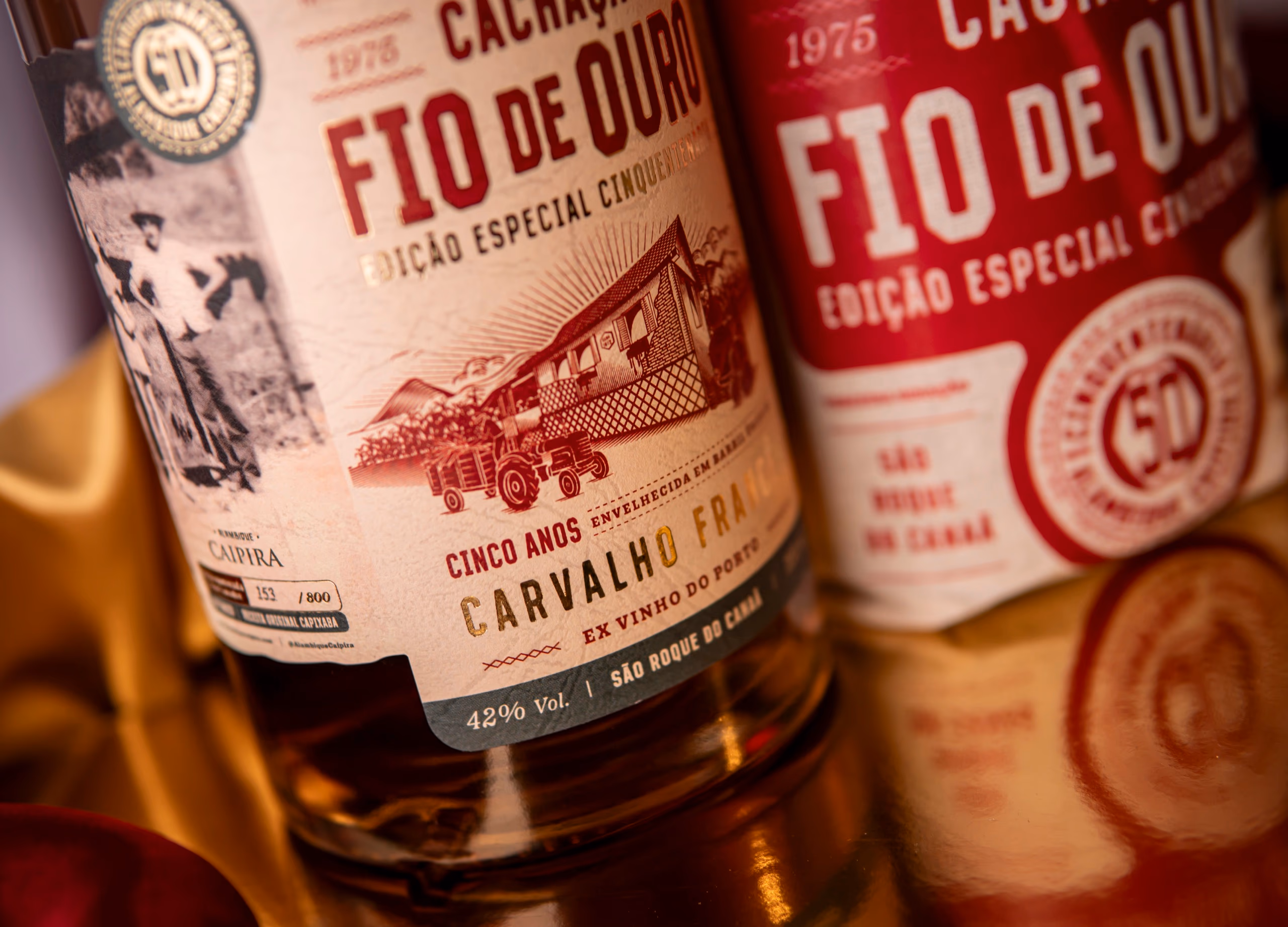 Garrafa da Cachaça Cinquentenária ao lado do saco de estopa e de canas de açúcar