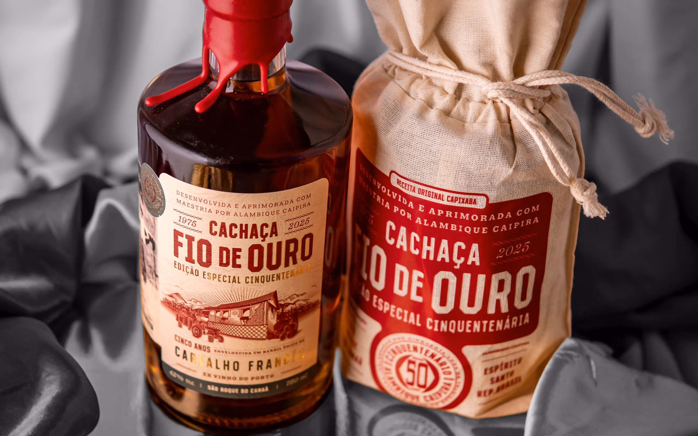Garrafa da Cachaça Cinquentenária ao lado do saco de estopa e de canas de açúcar